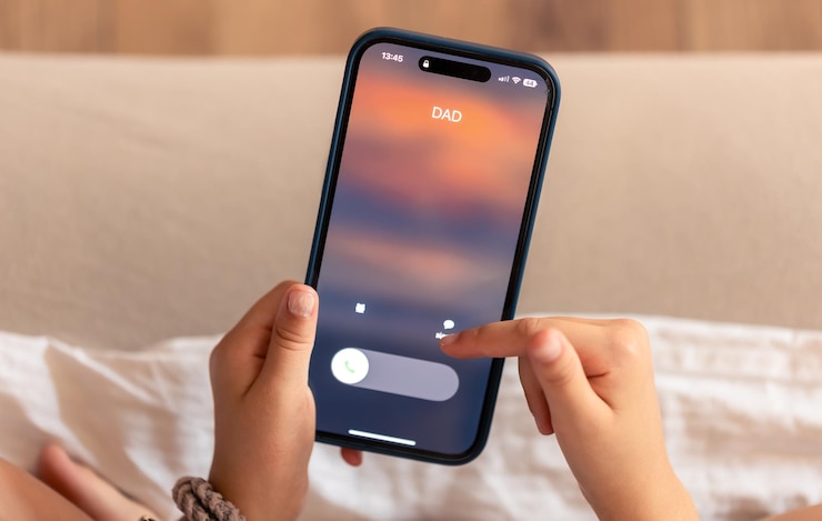 Photo close up of child hands holding phone with dads incoming call on display