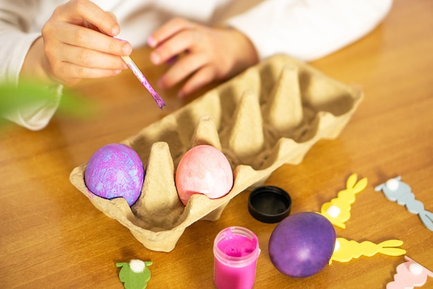 Закрытие детских рук, рисующих пасхальные яйца на деревянном столе Счастливой Пасхи Подготовка к Пасхе
