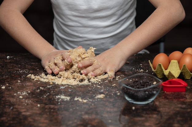 Foto chiudere le mani del bambino che preparano i biscotti in cucina