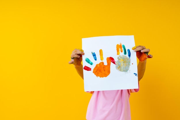 Close-up of child holding paper against yellow background