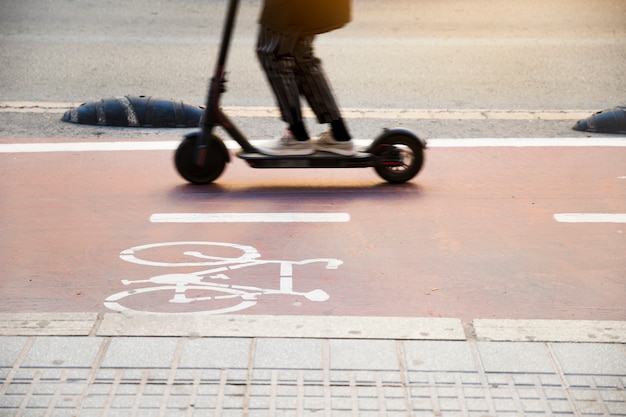 Close-up of a child riding kick scooter on cycle lane