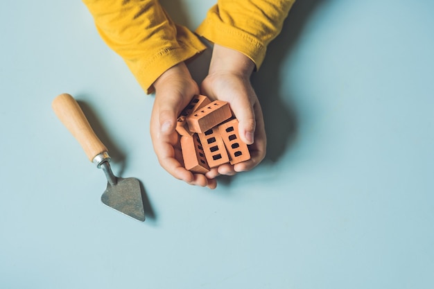 Close up of child's hands playing with real small clay bricks at the table