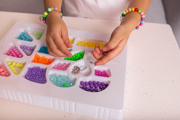 Крупный план детских рук с разноцветными бусинами для творчества