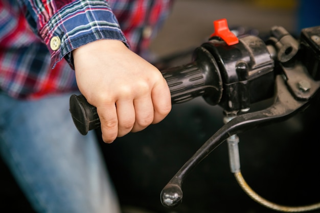 Close-up children's hand on the handle of an old motorcycle