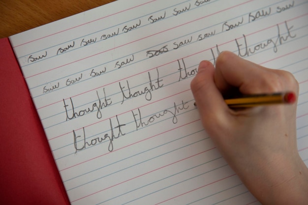 Photo close up of a childs hand practicing handwriting in school