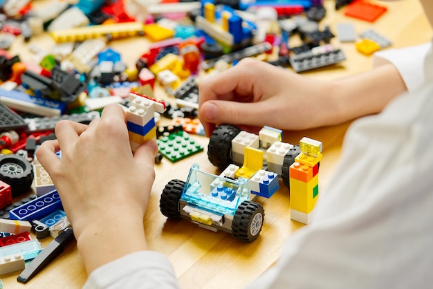 Close up of childs hands playing with colorful plastic bricks at the table development of fine motor skills in children favorable for the development of brain activity developing toys