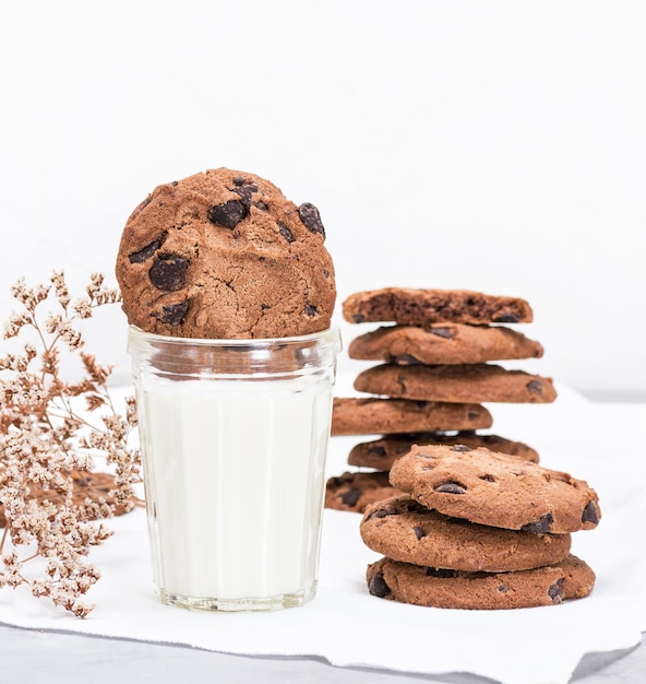 Photo close-up of chocolate chip cookies and milk on table against white background