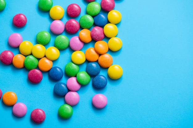 Close up of chocolate egg and candy drops on blue surface