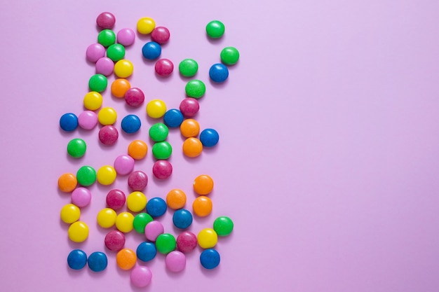 Close up of chocolate egg and candy drops on pink surface
