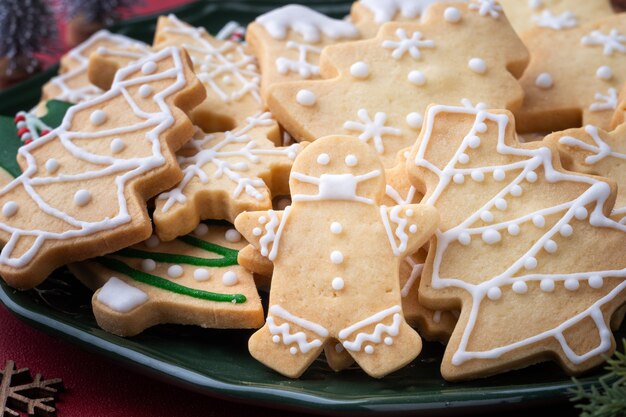 Close up of Christmas decorated sugar cooikes in a plate on red table background.