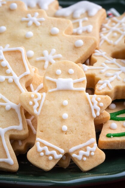 Close up of christmas decorated sugar cookies in a plate on red table background