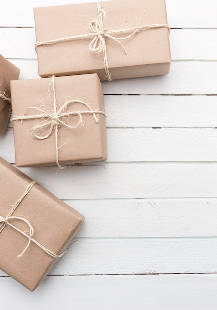 Close up Christmas style rustic brown paper package tied up with strings. White wood background.