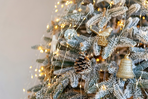Close up Christmas tree decorated with cone, golden ornaments and christmas lights, copy space. New Year background concept. Selective focus.