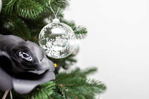 Photo close-up of a christmas tree decorated with transparent balls and black paper roses. christmas holiday concept