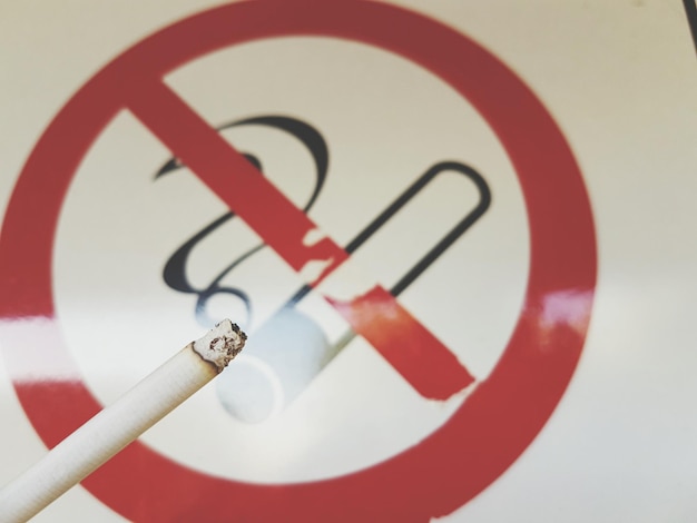 Close-up of cigarette by smoking sign