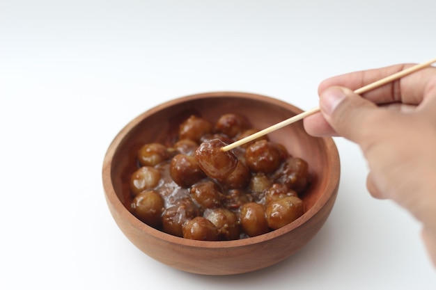 близкий взгляд на цилок, сделанный из муки тапиоки и вкусного арахисового соуса, подаваемого в деревянной чаше, изолированной на белом фоне