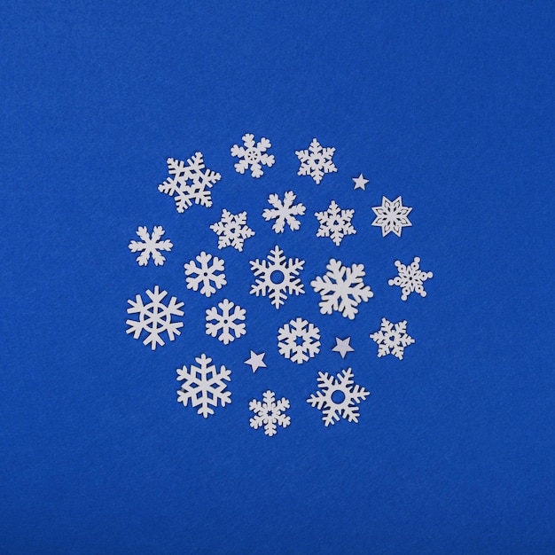 Photo close up circle of white wooden snowflakes christmas decoration over blue felt background table top view flat lay