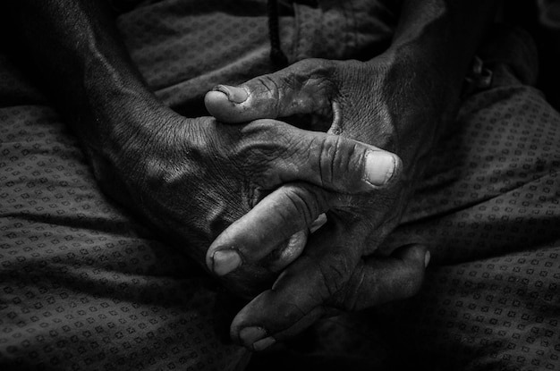 Photo close-up of clasped hands on bed