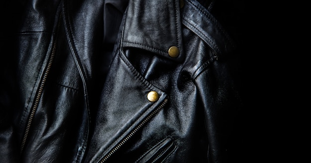 Close up classic black leather jacket with gold botton in dark background