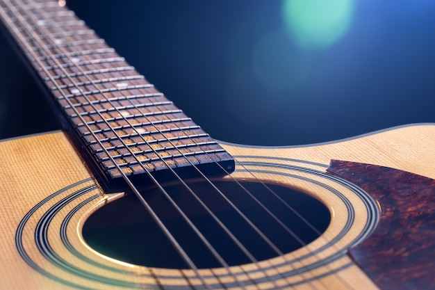 Primo piano di una chitarra acustica classica su uno sfondo sfocato con bokeh.