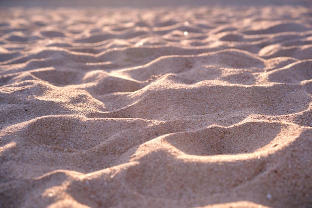 Close up of clean yellow sand surface covering seaside beach illuminated with evening light Travel and vacations concept