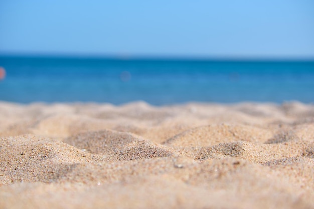 Close up of clean yellow sand surface covering seaside beach with blue sea water on background Travel and vacations concept