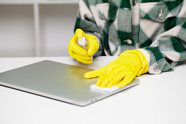 Close up of cleaner in yellow gloves wipes dust in the office