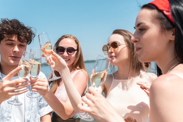 クローズアップ、乾杯。ビーチリゾートでの季節のごちそう。晴れた夏の日に祝って、休んで、楽しんでいる友人のグループ。幸せで陽気に見えます。お祝いの時間、ウェルネス、休日、パーティー。