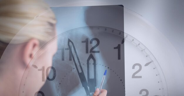 Close up of clock against caucasian female doctor examining x-ray report