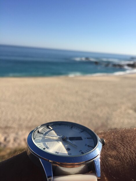 Foto prossimo piano dell'orologio sulla spiaggia contro un cielo limpido