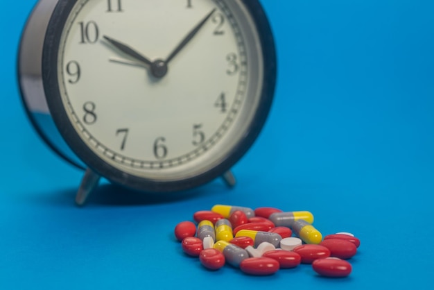 Foto close-up di orologio e pillole su sfondo blu