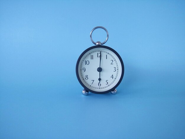 Close-up of clock on table against blue background