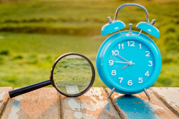 Close-up of clock with magnifying glass on wooden table