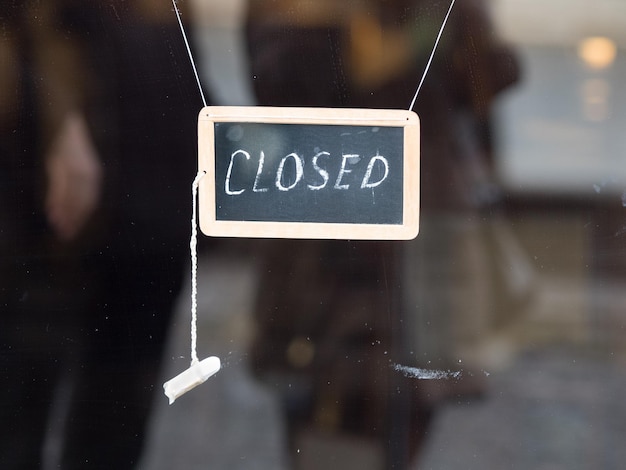 Close-up of closed text on blackboard hanging at store