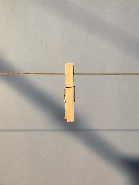 Photo close-up of clothespin hanging on clothesline against wall