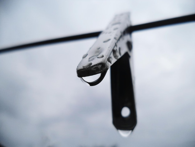 Close-up of clothespin hanging on clothesline during rainy season