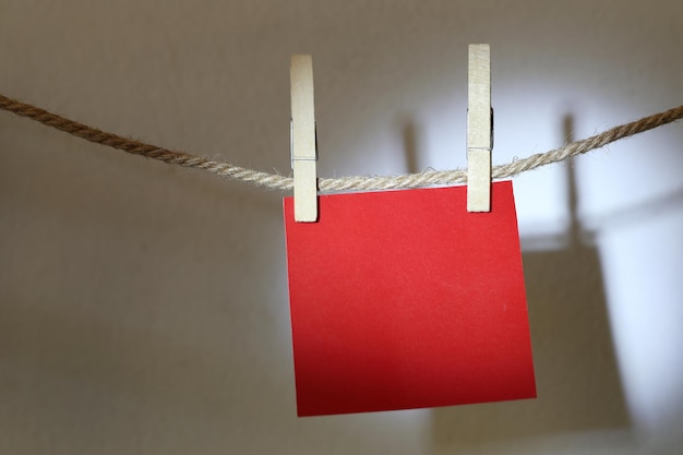 Photo close-up of clothespins hanging on rope against wall