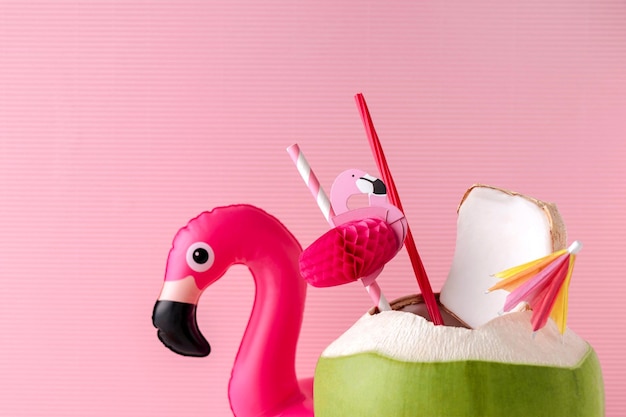 Photo close-up of coconut water and inflatable flamingo against pink background