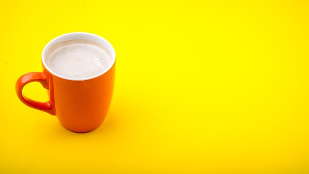 Close-up of coffee cup against orange background