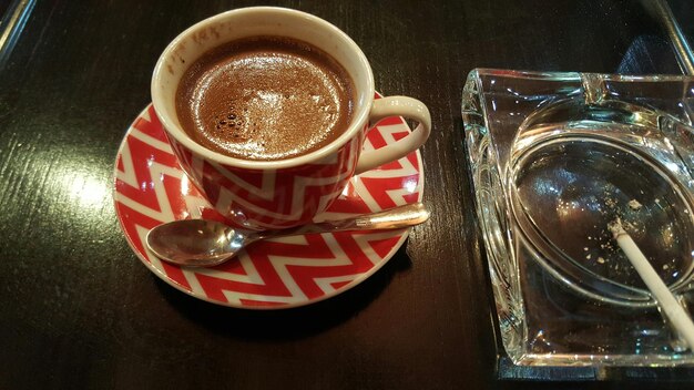 Close-up of coffee cup and ashtray on table