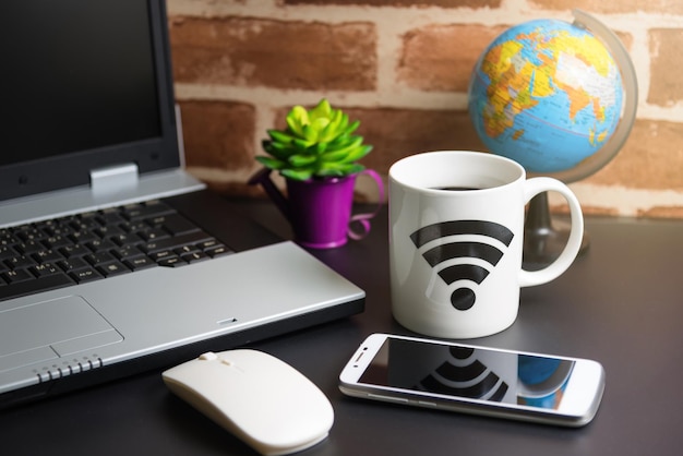 close-up of coffee cup by laptop on table
