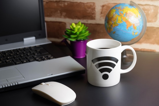 close-up of coffee cup by laptop on table