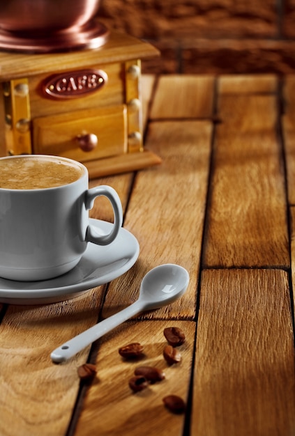 Крупный план кофейной чашки и кофемолки на деревянном столе