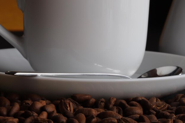 Foto close-up di una tazza di caffè e un cucchiaio su un piatto di chicchi di caffè arrostiti