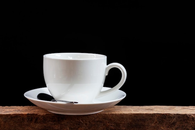 Foto close-up di una tazza di caffè sul tavolo contro uno sfondo nero
