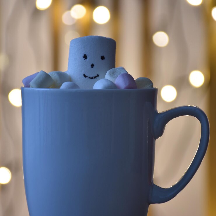 Photo close-up of coffee cup on table with christmas lights in background