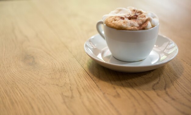 Close-up of coffee cup with creamy froth on table at cafe