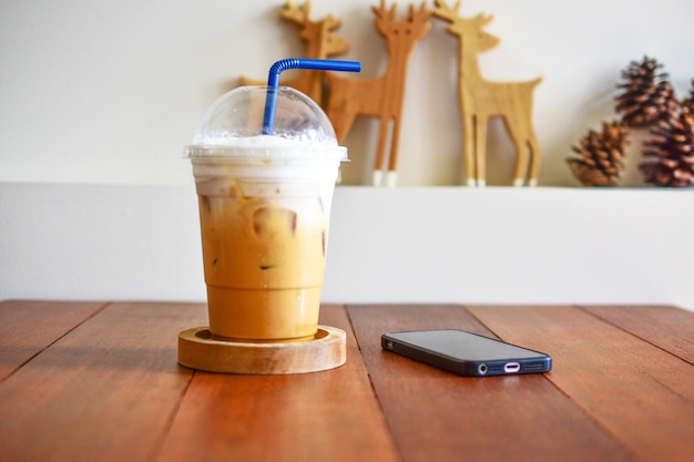 Photo close-up of coffee in disposable cup by mobile phone on table