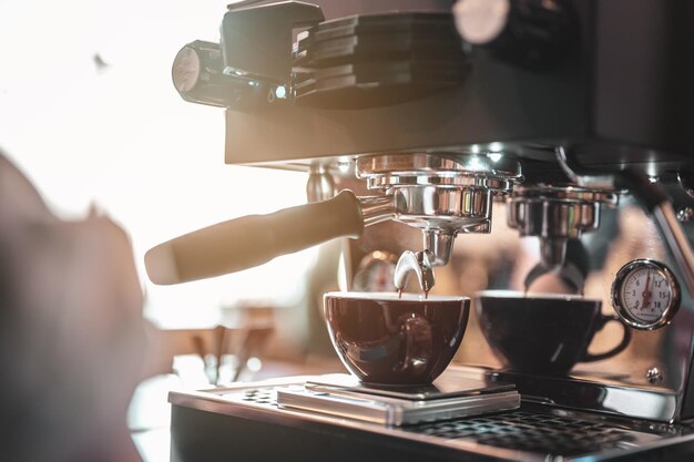 Close-up coffee maker that is professionally extracting coffee by barista with a deep white glass in the evening sun light. coffee, extraction, deep, machine, make, barista concept.