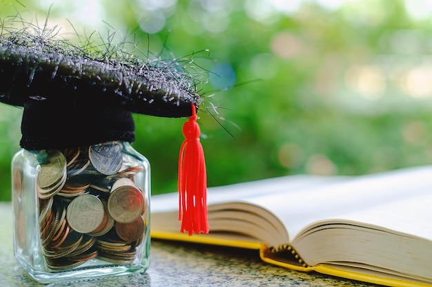 Photo close-up of coin jar with hat and book on table